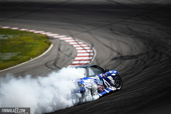 A car on a track with smoke from the rear tires