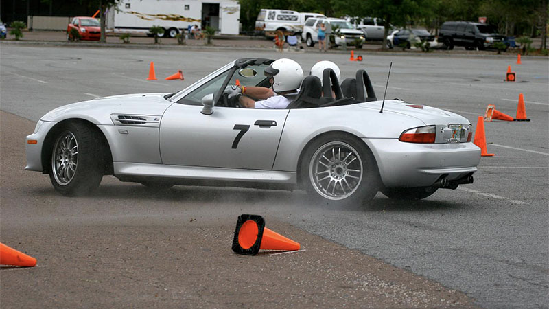 A silver Miata runs an autocross course with cones knocked over