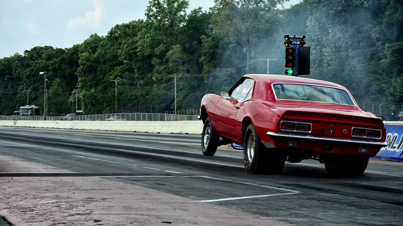 A muscle car revs before launch on a drag racing strip