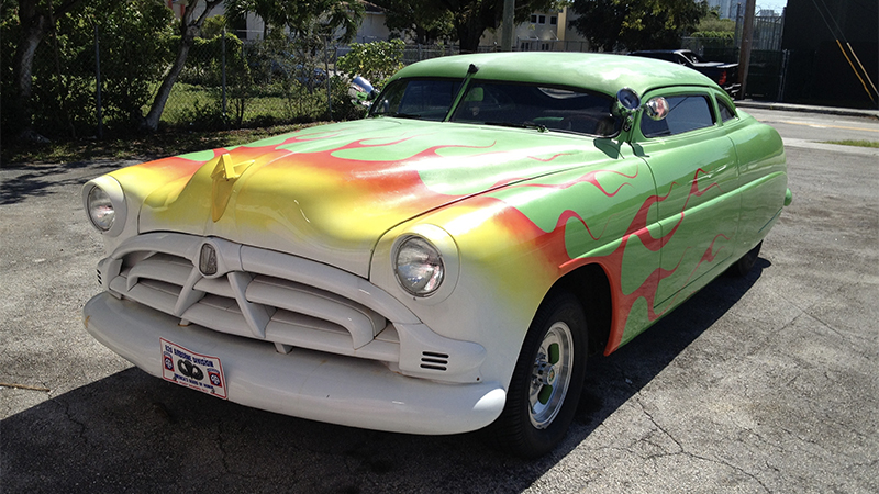 a lowrider with colorful flame paint from the front grille that meets green body paint