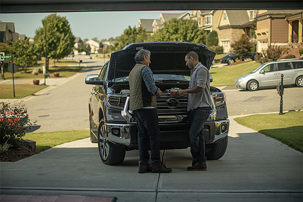 father and son working on an SUV in a driveway