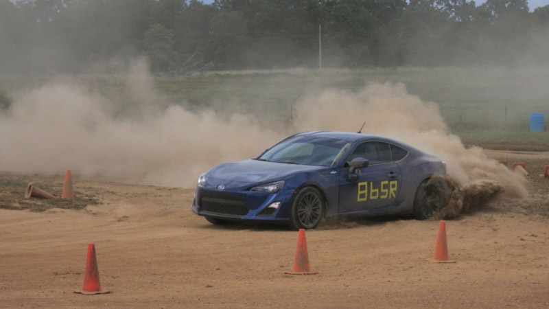 a blue BRZ competing on a dirt track marked by cones