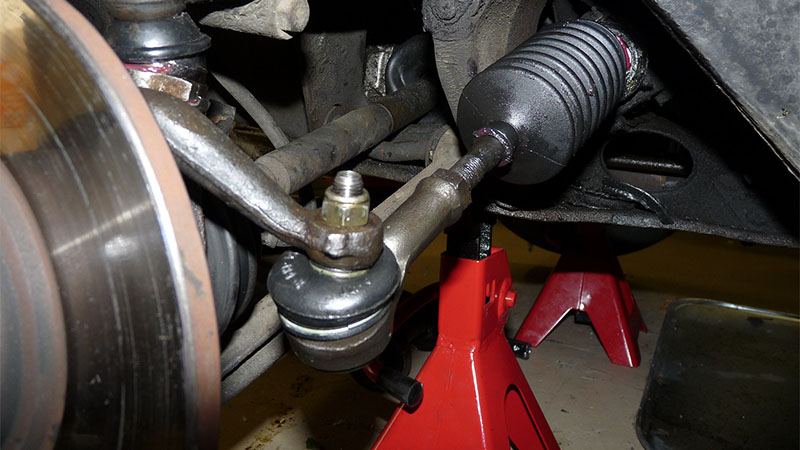 With the vehicle wheel removed, the tie rod end is visible at the end of the power steering rack.