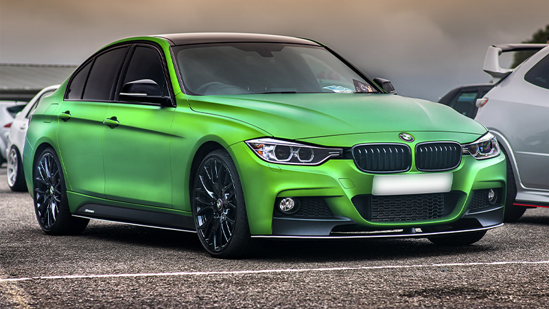 a wrapped bright green BMW 3 Series with tinted windows and black wheels