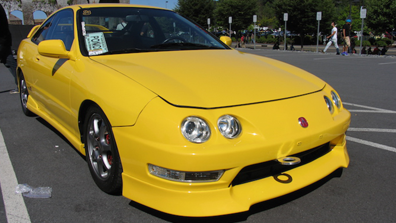 A yellow Acura Integra in a parking lot.