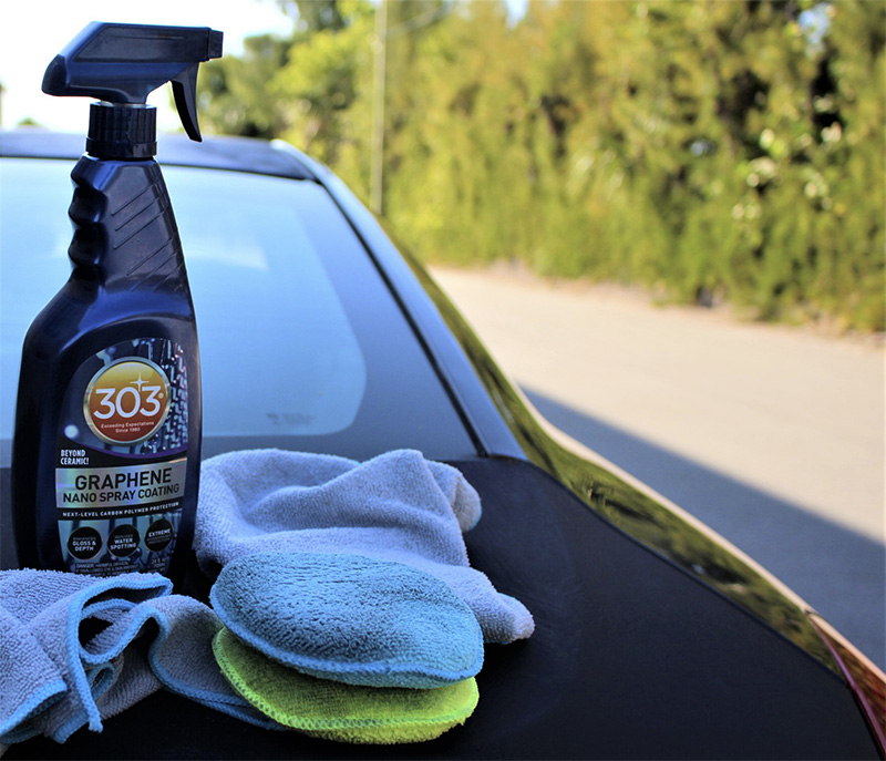 bottle of 303 Graphene Nano Spray next to microfiber towels on the back of a car 