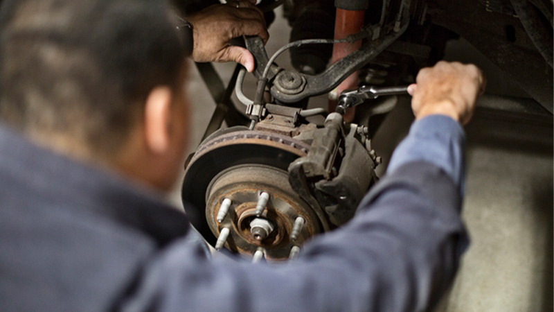 a man uses a ratchet to tighten a caliper bolt on his brakes