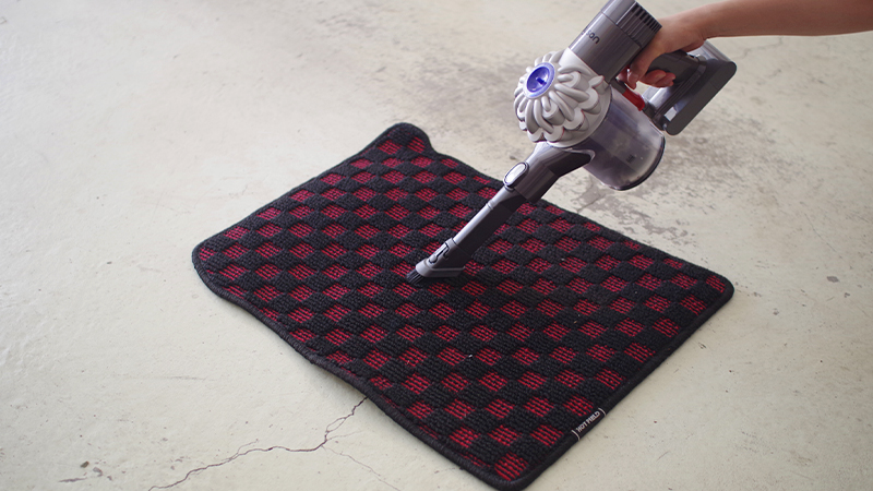 vacuuming a car mat