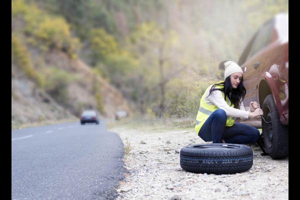 woman changing tire on the side of the road