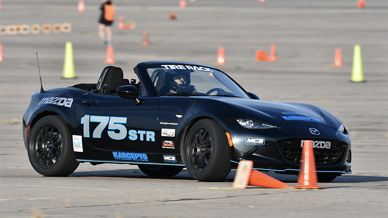 A Mazda on an autocross track marked by orange and yellow cones