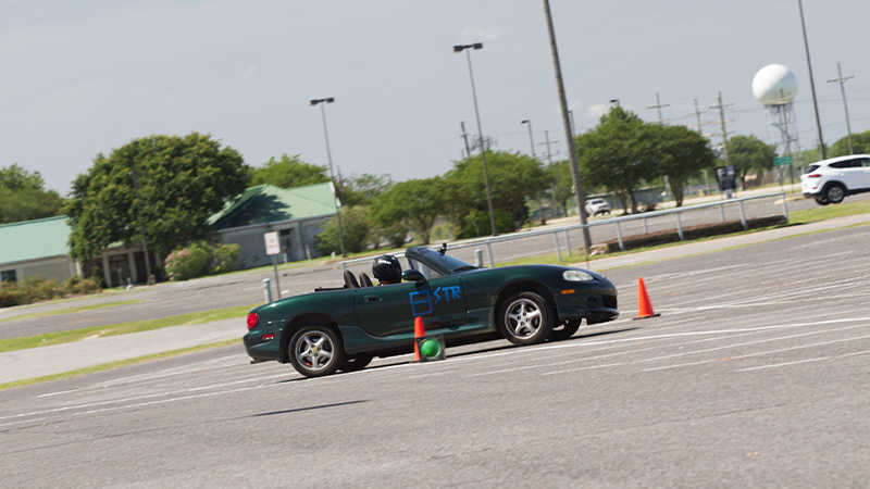 A Mazda on an autocross track, between two orange cones