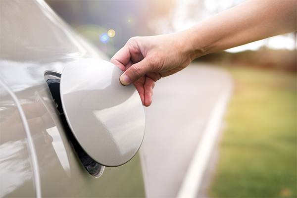 a man's hand opening a fuel lid on the side of a car