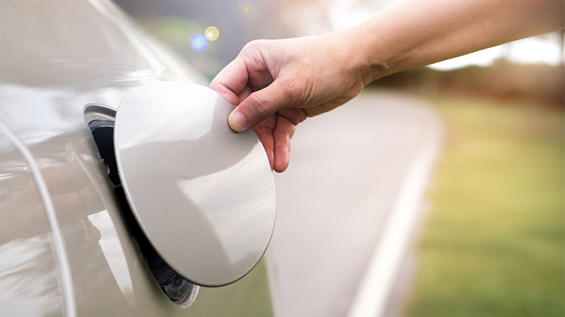 a man's hand opening a fuel lid on the side of a car