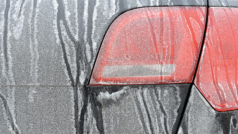 left rear corner of a black vehicle that has been covered in road salt
