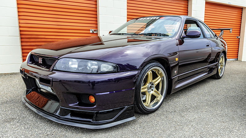 Custom purple GTR parked in front of storage units