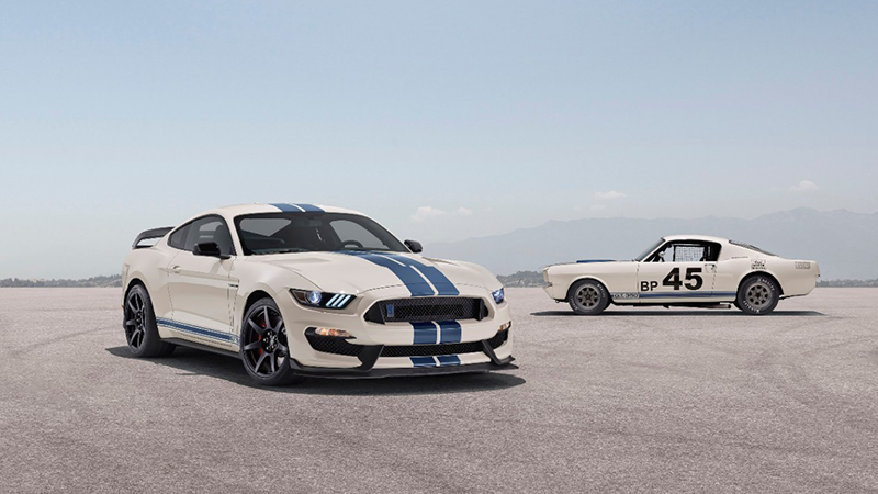 Two white and blue Mustangs posed in a desert.