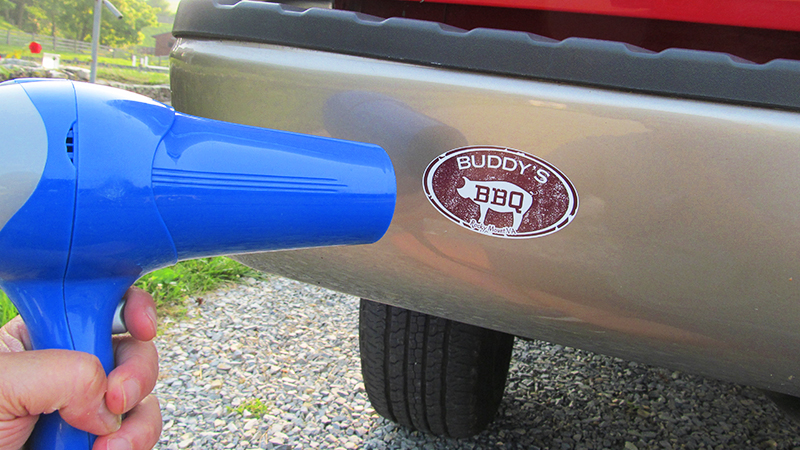 holding a hair dryer up to a bumper sticker